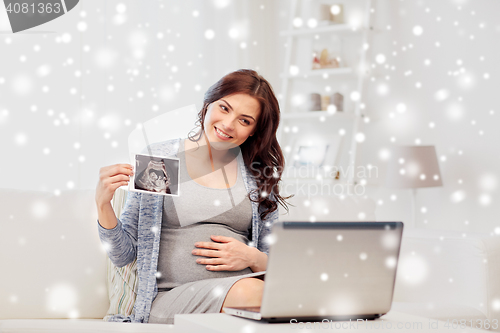 Image of pregnant woman with ultrasound image and laptop
