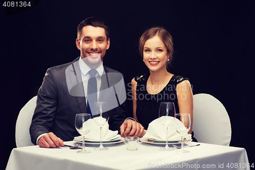 Image of smiling couple holding hands at restaurant