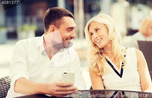 Image of happy couple with smatphone at city street cafe