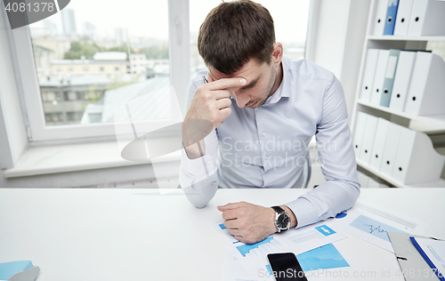 Image of stressed businessman with papers in office