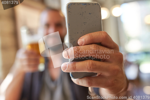 Image of close up of man with smartphone and beer at pub