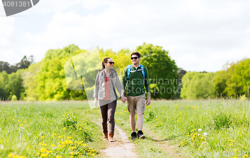 Image of happy couple with backpacks hiking outdoors