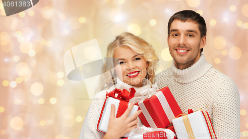 Image of happy couple in sweaters holding christmas gifts 