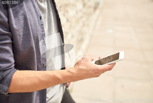 Image of close up of man with smartphone at stone wall