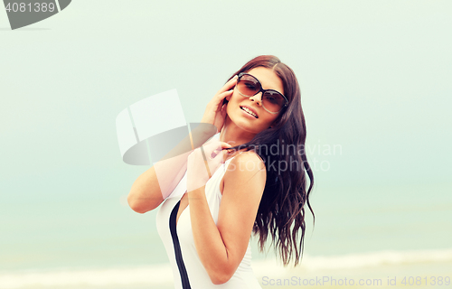 Image of smiling young woman with sunglasses on beach