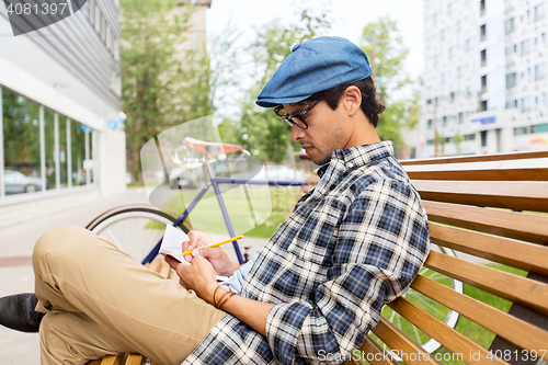Image of man with notebook or diary writing on city street