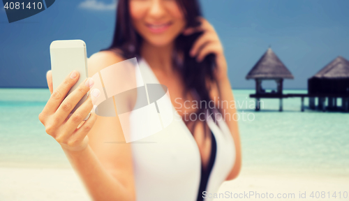 Image of young woman taking selfie with smartphone