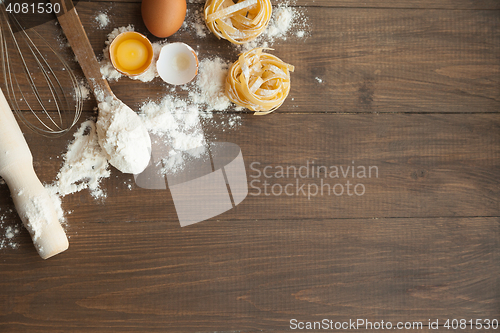 Image of Cuisine composition with fettuccine cracked eggs,kitchenware, flour.