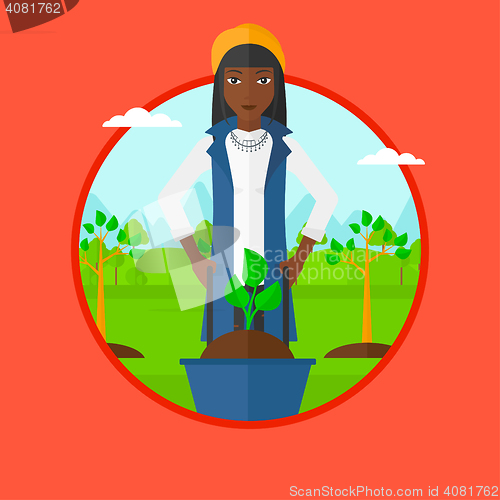 Image of Woman pushing wheelbarrow with plant.