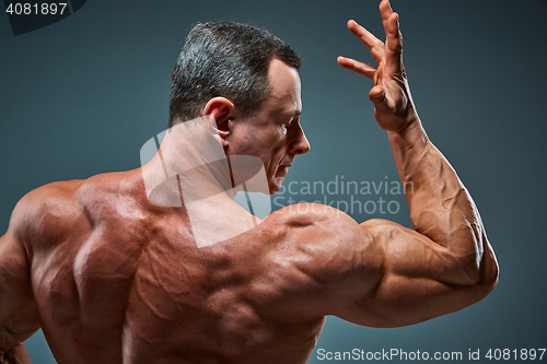 Image of torso of attractive male body builder on gray background.