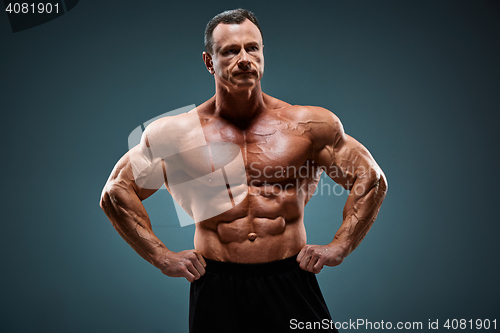 Image of torso of attractive male body builder on gray background.