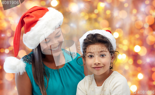 Image of happy mother and little girl in santa hats