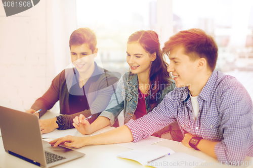 Image of three smiling students with laptop and notebooks