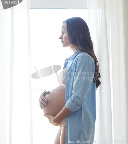 Image of happy pregnant woman with big bare tummy at home