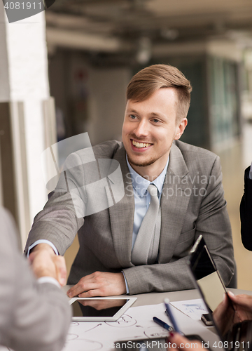 Image of smiling businessman making handshake at office