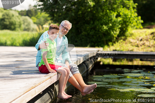 Image of grandfather and grandson sitting on river berth