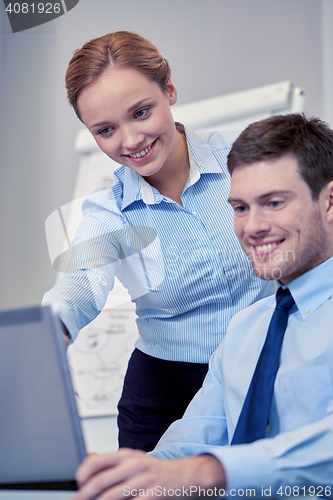 Image of smiling businesspeople with laptop in office