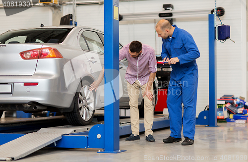 Image of auto mechanic with clipboard and man at car shop