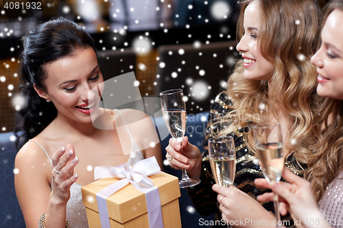 Image of happy women with champagne and gift at night club