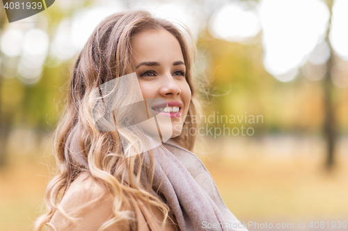 Image of beautiful happy young woman smiling in autumn park