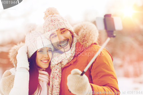 Image of happy couple taking selfie by smartphone in winter