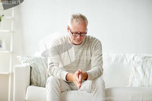 Image of  senior man sitting on sofa at home and thinking