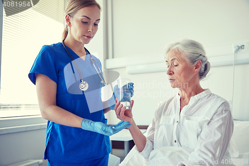 Image of nurse giving medicine to senior woman at hospital