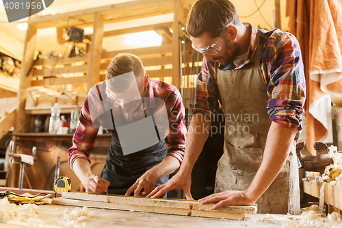 Image of carpenters with ruler and wood plank at workshop