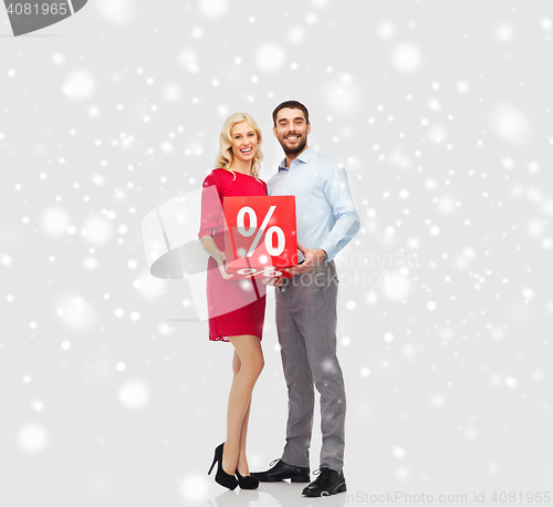 Image of happy couple with red sale sign over snow