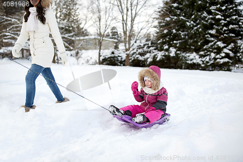 Image of happy mother pulling sled with child in winter