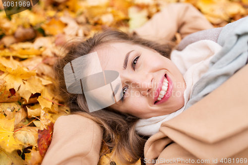 Image of beautiful happy woman lying on autumn leaves
