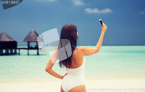 Image of young woman taking selfie with smartphone