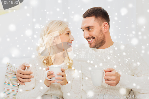 Image of happy couple with cups drinking tea at home