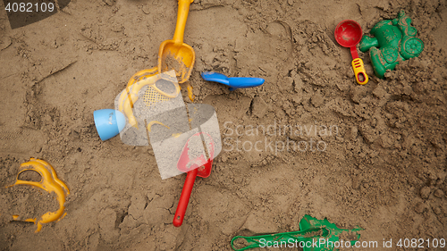 Image of set of color plastic toys on a sand