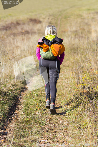 Image of Young woman walking by hiking trail