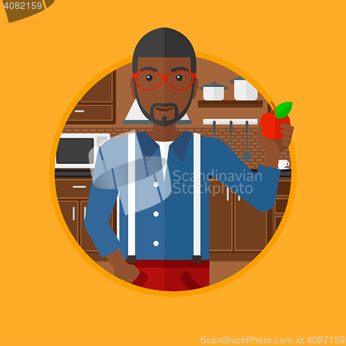Image of Young man with apple in the kitchen.