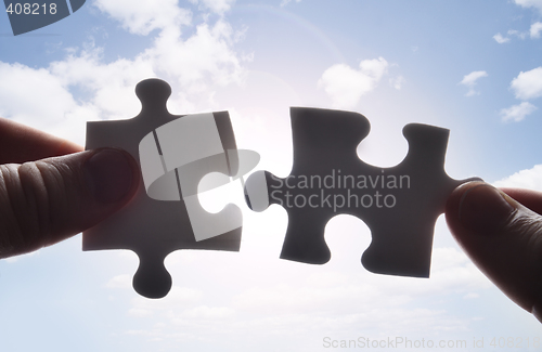 Image of Hands trying to fit two puzzle pieces together