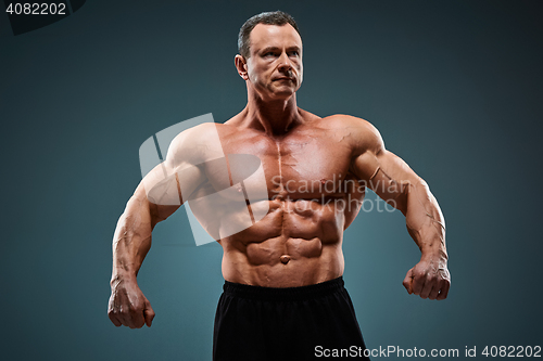 Image of torso of attractive male body builder on gray background.