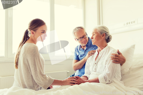 Image of family visiting ill senior woman at hospital