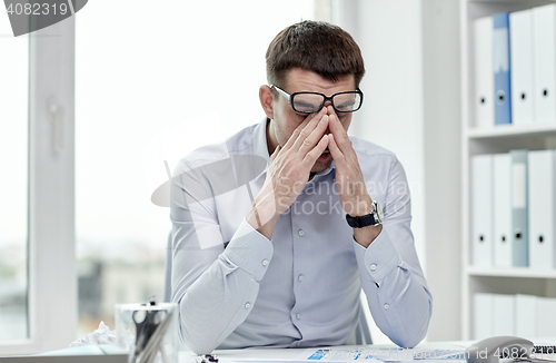 Image of tired businessman with eyeglasses in office