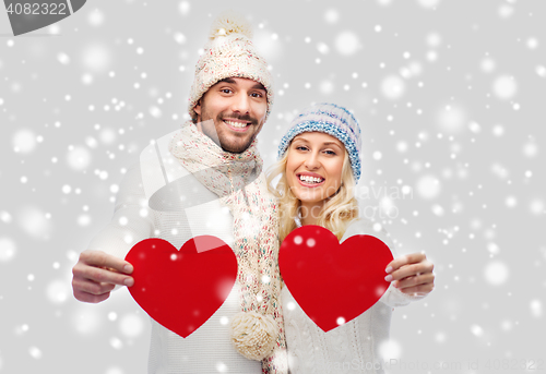 Image of smiling couple in winter clothes with red hearts