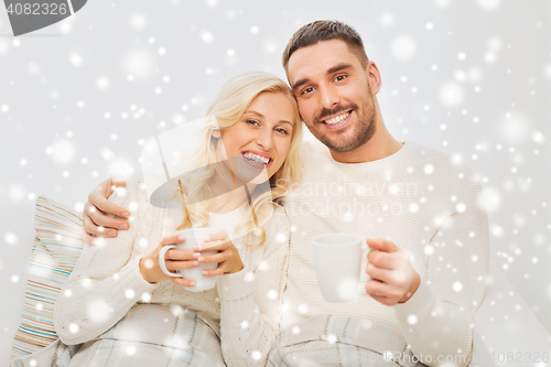 Image of happy couple with cups drinking tea at home