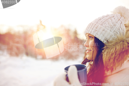 Image of happy young woman with tea cup outdoors in winter