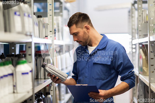 Image of auto mechanic with clipboard at car workshop