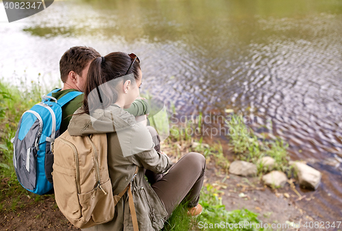 Image of couple with backpacks sitting on river bank