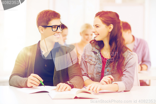 Image of two teenagers with notebooks and book at school