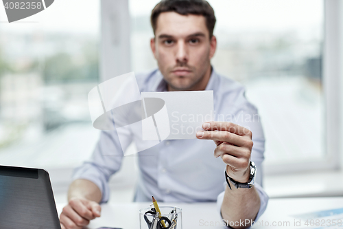 Image of businessman showing blank paper card at office