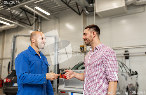 Image of auto mechanic giving key to man at car shop