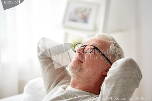Image of smiling senior man in glasses relaxing on sofa