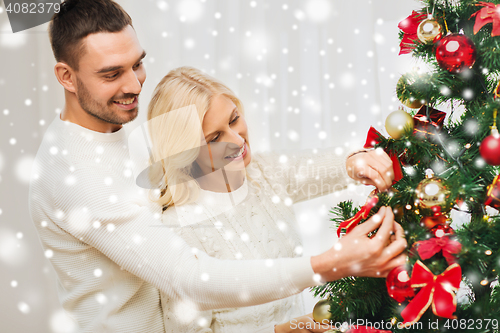 Image of happy couple decorating christmas tree at home